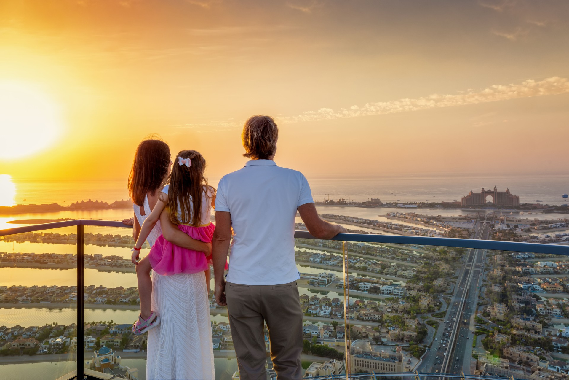 A family on holidays enjoys the sunset view of The Palm island in Dubai