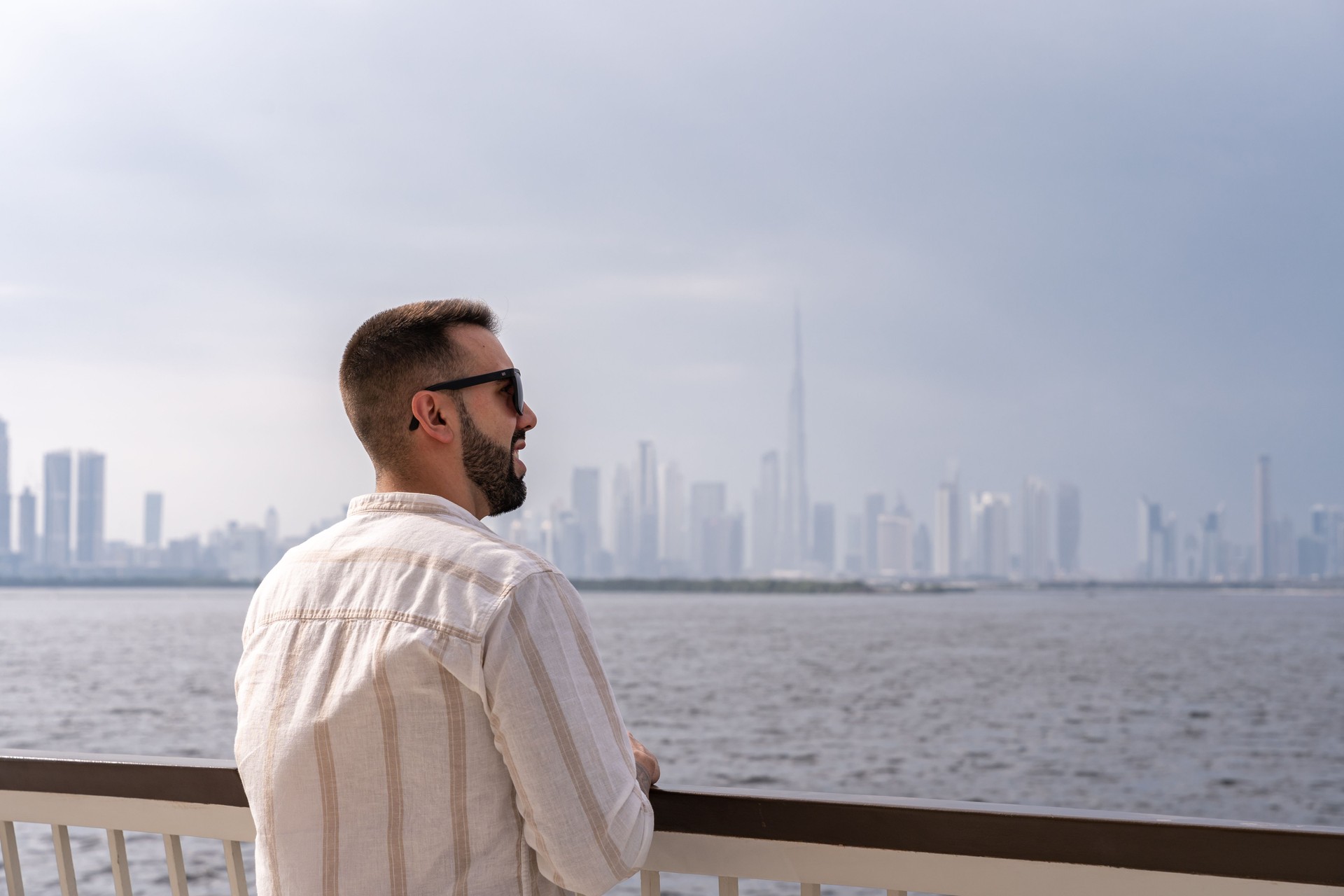 Close-up of young man on a lookout point overlooking the Dubai skyline.